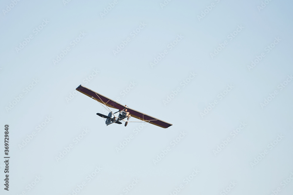 Fototapeta premium Plane flying high up in the cloudless sky at daytime. Male pilot