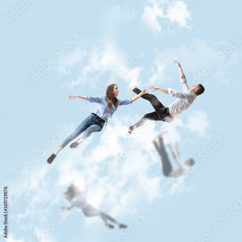 Mid-air beauty cought in sky. Full length shot of attractive young woman and man hovering in air and keeping eyes closed. Levitating in free falling, lack of gravity. Freedom, emotions, artwork