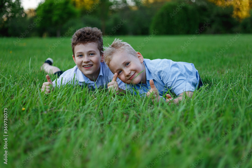 Fototapeta premium Two cheerful friends lying on green meadows in the park, after school.