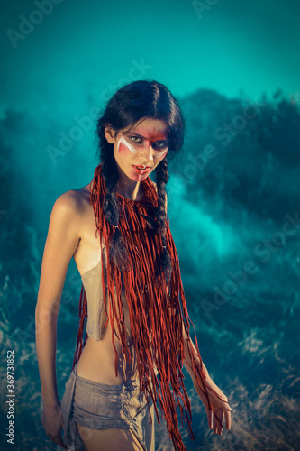 Bild auf Leinwand red-skinned Indian girl with red makeup on her face posing in yellow grass