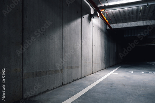 Sci fi looking dark and moody underground parking lot with fluorescent lights on. Long hall