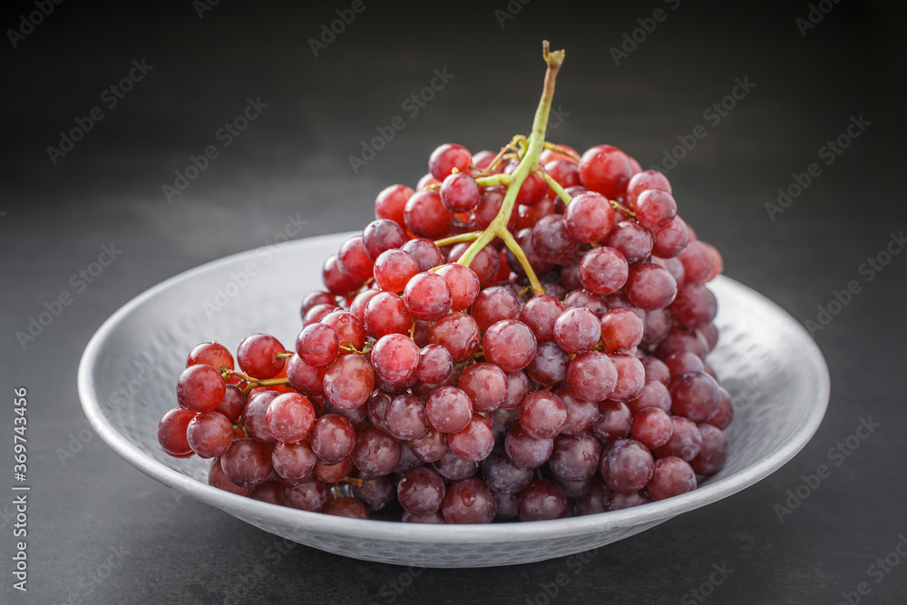 fresh red grape in nice metal plate on dark grey tone texture background fresh red grape in nice metal plate on dark grey tone texture background