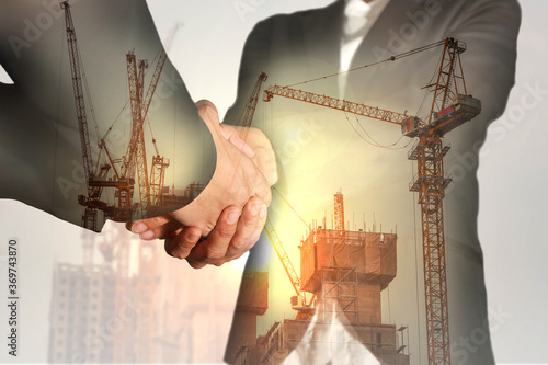 Double exposure of businesswomen double handshake, construction crane, bulilding and sunlight of sunset as business, commitment, congratulation, welcome and industry concept. photo