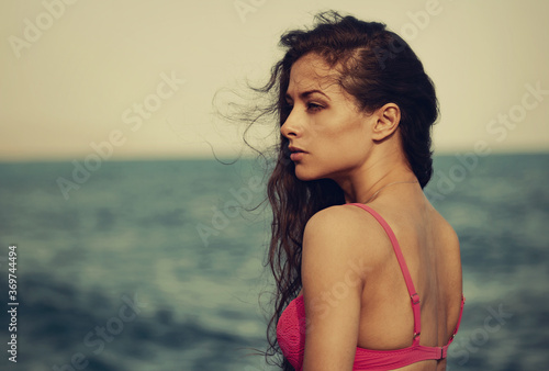 Beautiful serious thinking woman looking on the blue sea on summer holadays with empty copy space. Healthy face skin and long windy hair of female model. Closeup fashion profile portrait. Vintage