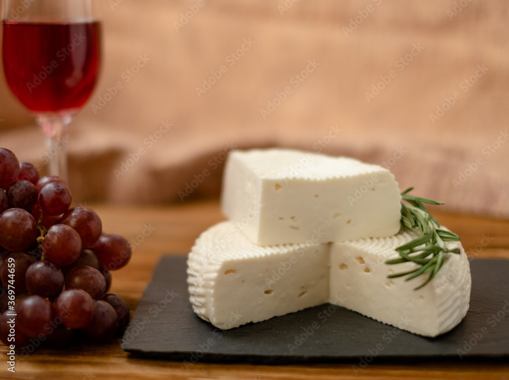 Goat cheese, grapes and wine lie on a wooden table. Cheese at home. Goat cheese, grapes and wine lie on a wooden table. Cheese at home.
