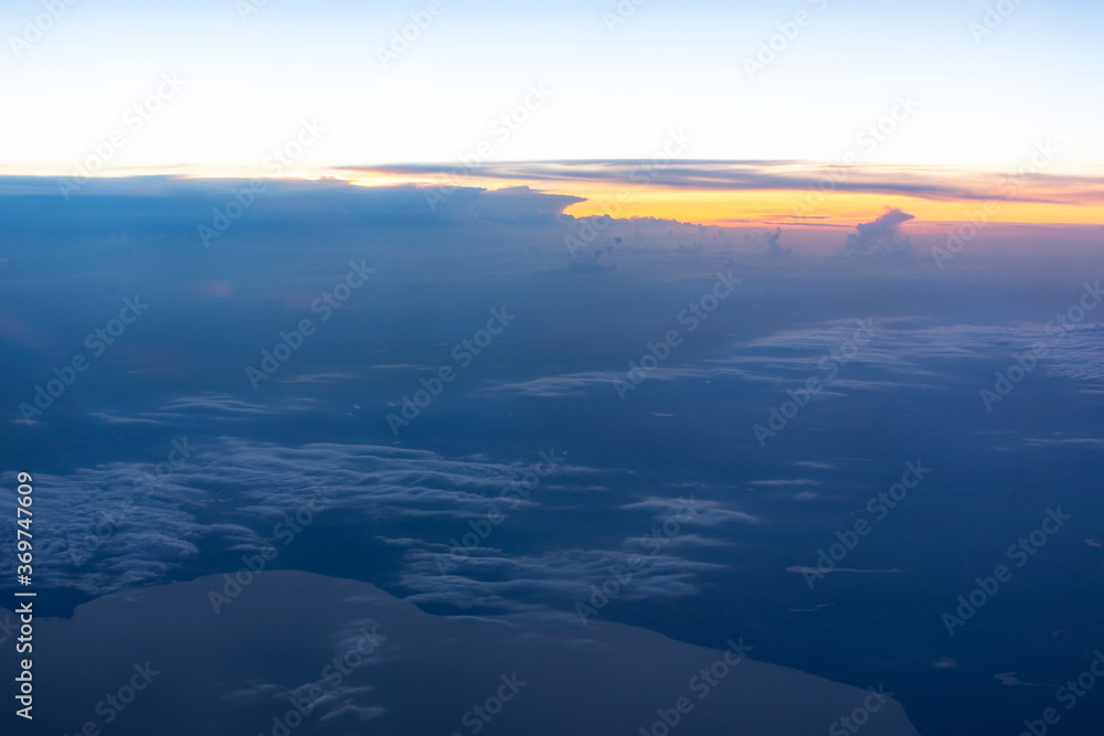 Obraz premium View from the plane window to the evening sky. Beautiful landscape from the plane window. Flying above the clouds. Warm blue shades of the twilight sky.