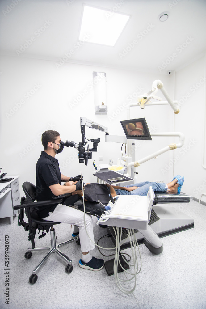 Male dentist examining woman looking on the teeth with professional microscope in the dental office Male dentist examining woman looking on the teeth with professional microscope in the dental office