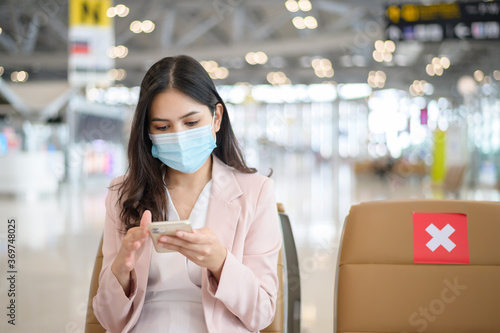 A business woman is wearing protective mask in International airport, travel under Covid-19 pandemic, safety travels, social distancing protocol, New normal travel concept