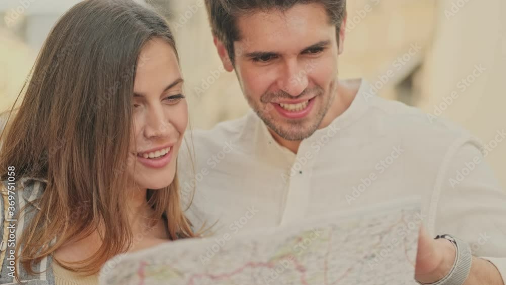 Happy young pretty couple studying the city map and talking while standing together on the street Happy young pretty couple studying the city map and talking while standing together on the street