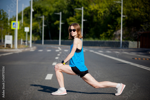 young athletic woman with short hair doing sports warm-up before jogging workout