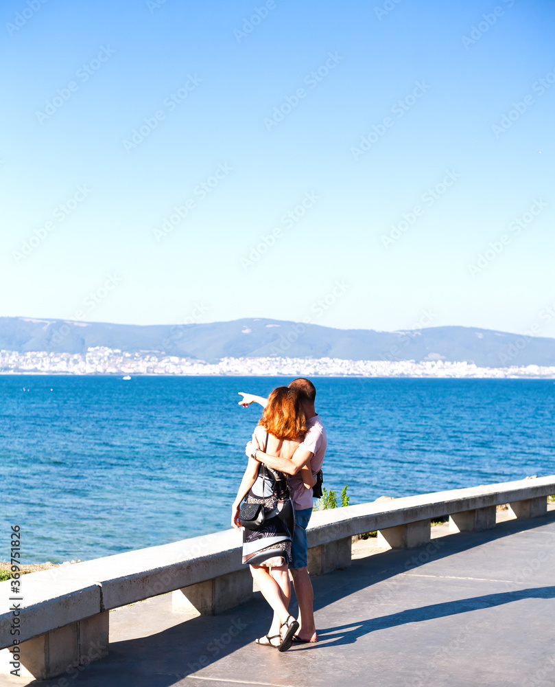 Young happy couple standing on seashore and hugging each other. Back view. Vacation. Bulgaria. Young happy couple standing on seashore and hugging each other. Back view. Vacation. Bulgaria.