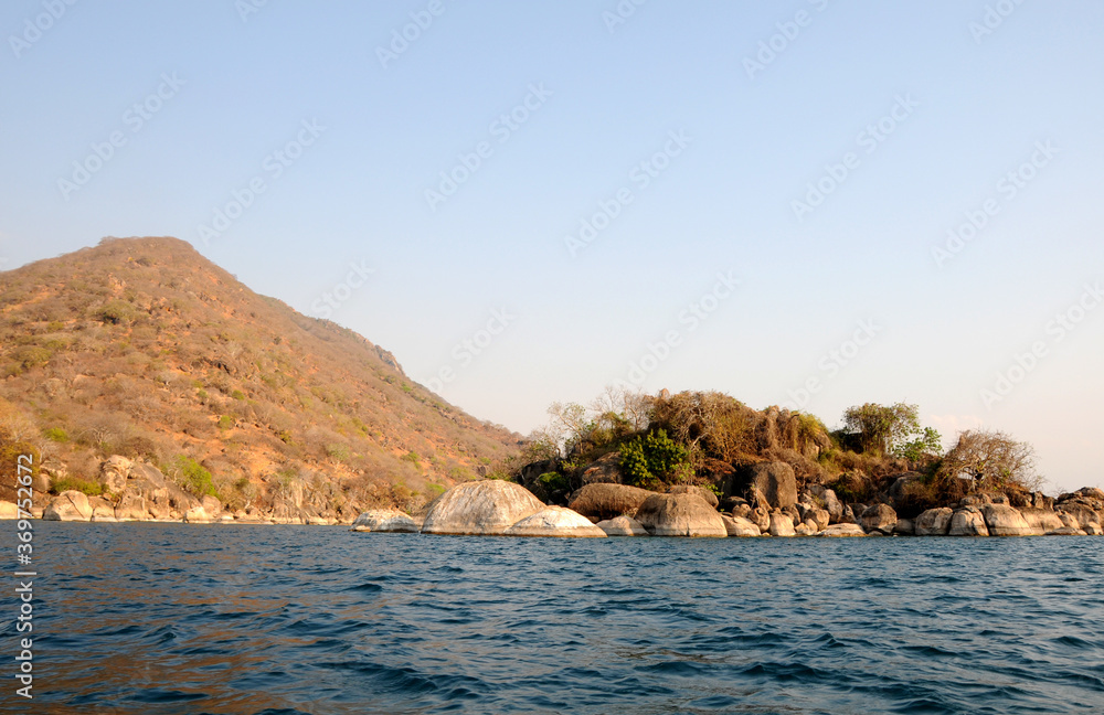 A beautiful contrast between the calmness of bright blue water against the rugged red shoreline surrounding Lake Malawi A beautiful contrast between the calmness of bright blue water against the rugged red shoreline surrounding Lake Malawi