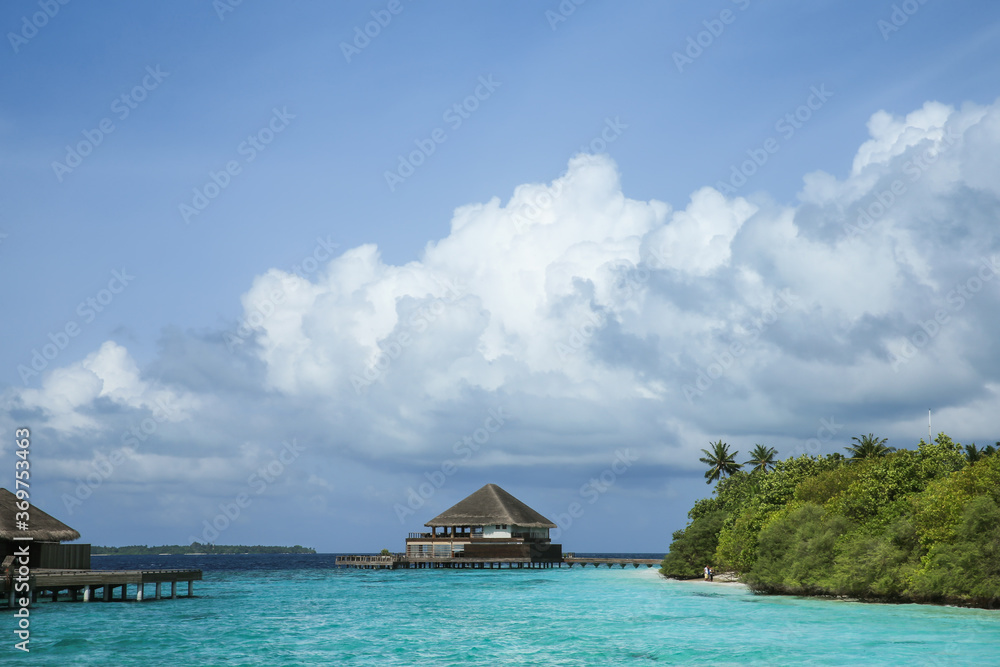 Maldives sea, clouds, palms and villas.