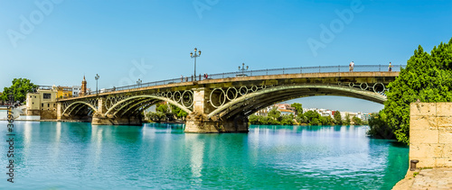 A view on the east bank of the river Guadalquivir towards the Triana Bridge in Seville, Spain in the summertime photo