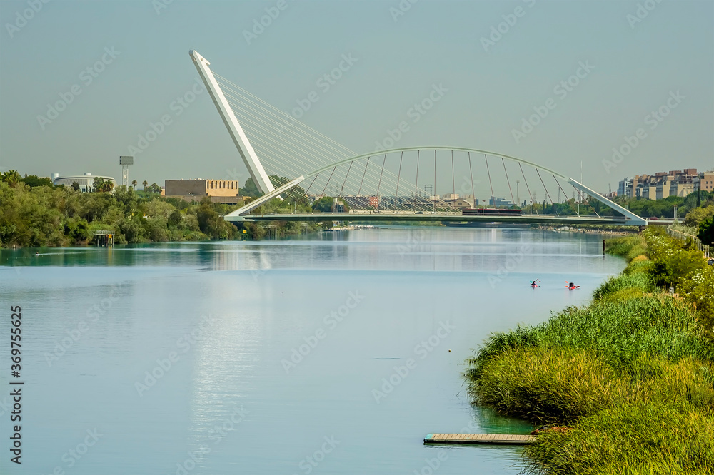 Fototapeta premium A view from the east bank of the river Guadalquivir towards the Barqueta Bridge in Seville, Spain in summertime