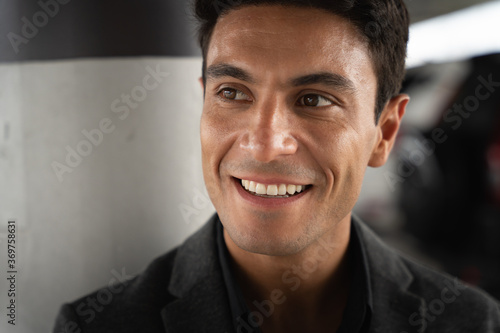 Close up portrait of middle-aged Hispanic businessman looking sideways and little smile with confidence in dark tone atmosphere with copy space, confident and stylish, CEOs style, boss lifestyle.