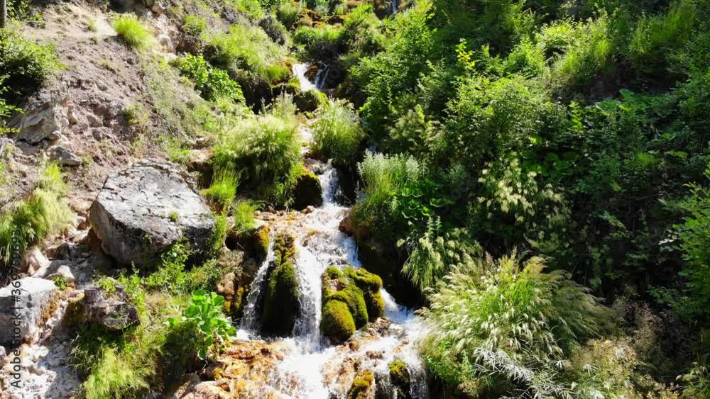 Drone shot of beautiful mountain waterfall with fast flowing water and rocks, streams and cascades with moss and grass in forest. Seasonal travel outdoor beauty in nature Sopotnica in Serbia Drone shot of beautiful mountain waterfall with fast flowing water and rocks, streams and cascades with moss and grass in forest. Seasonal travel outdoor beauty in nature Sopotnica in Serbia
