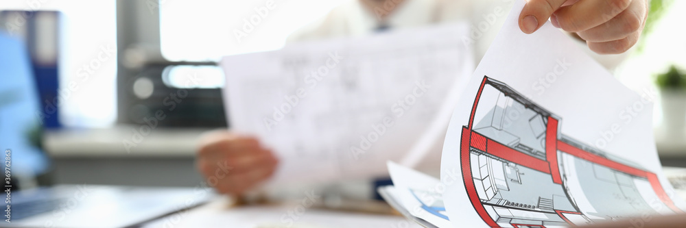 Male designer sits at table and looks at floor plan. Interesting design home. Use two primary colors in interior. Choice colors for decoration. Find right color scheme. Home source positive energy Male designer sits at table and looks at floor plan. Interesting design home. Use two primary colors in interior. Choice colors for decoration. Find right color scheme. Home source positive energy