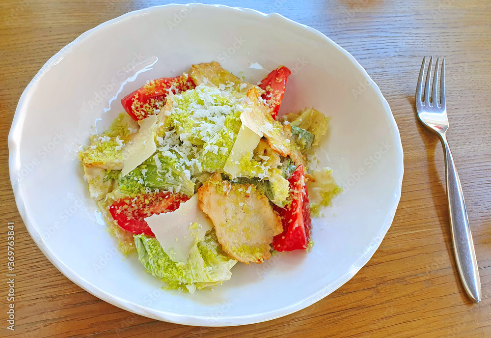 Caesar salad with fried chicken pieces and grated Parmesan cheese on a plate Caesar salad with fried chicken pieces and grated Parmesan cheese on a plate