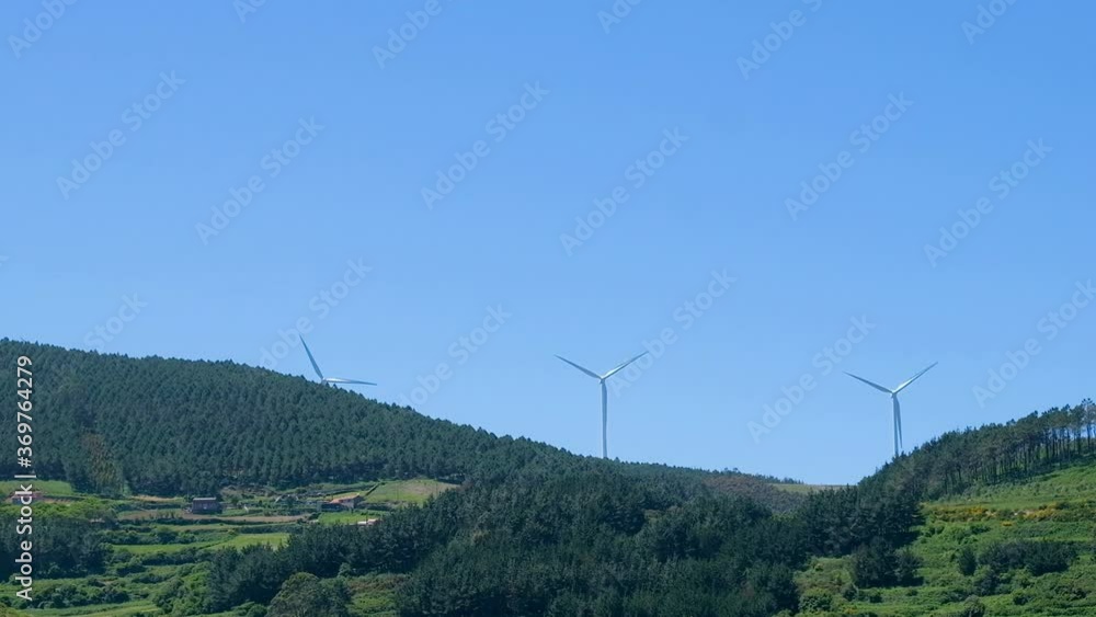 Rotating wind turbines on green hill, clean energy farm, eco technology Rotating wind turbines on green hill, clean energy farm, eco technology