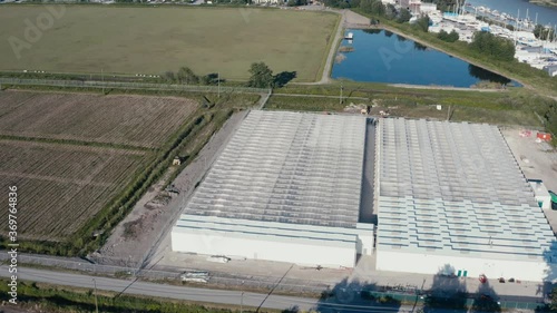 Aerial birds eye view fly over bobwire Givernment regulated secure cannabis farming pricessing facility greenhouse next to winery cranberry farm in Richmond BC Canada connected to Fraser RIver Port. photo