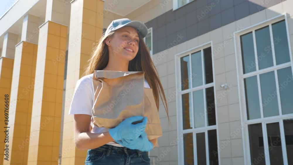 Delivery service girl in a medical gloves. A volunteer girl carries a bag of groceries during a pandemic outbreak. Online takeaway delivery. Delivery service girl in a medical gloves. A volunteer girl carries a bag of groceries during a pandemic outbreak. Online takeaway delivery.