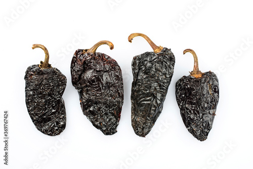 Dried Mexican black hot mulato chili offered as close-up on white background with copy space - free-form select photo