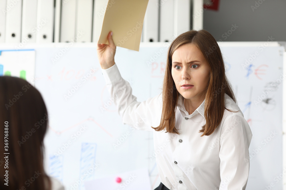Portrait of smart businesswoman looking at somebody with strange look in gorgeous eyes. Pretty business lady holding important charts and graphs. Accounting office concept Portrait of smart businesswoman looking at somebody with strange look in gorgeous eyes. Pretty business lady holding important charts and graphs. Accounting office concept