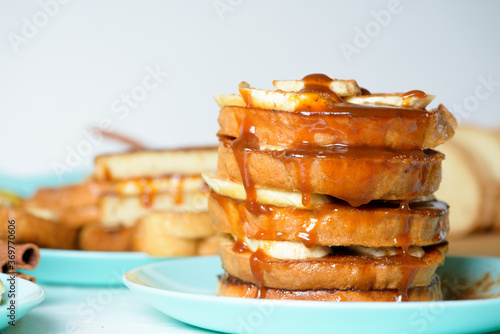 French toast with banana and homemade caramel with cinnamon, Breakfast dessert on a blue plate on a light background