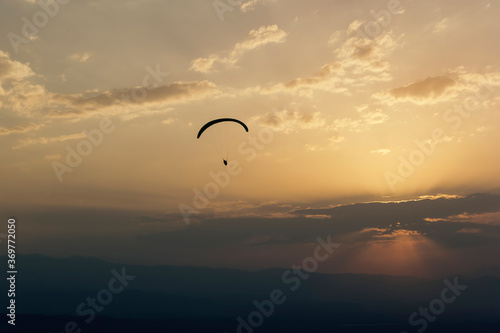 Paraglider flies in the clouds at sunset, background, blur