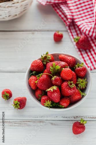 Fresh strawberries on ceramic bowl top view. Healthy food on white wooden table. Delicious, sweet, juicy and ripe berry background with copyspace for text