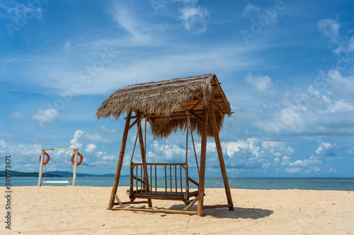 Wooden swing under a thatched roof on a sandy tropical beach near sea on island of Phu Quoc, Vietnam. Travel and nature concept photo