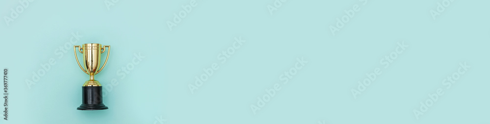 Simply flat lay design winner or champion gold trophy cup isolated on blue pastel colorful background. Victory first place of competition. Winning or success concept. Top view copy space Banner Simply flat lay design winner or champion gold trophy cup isolated on blue pastel colorful background. Victory first place of competition. Winning or success concept. Top view copy space Banner