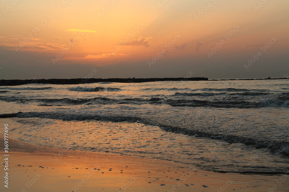 A beautiful and relaxing sunrise on the beach. Orange sky reflecting on the sea. Copy space