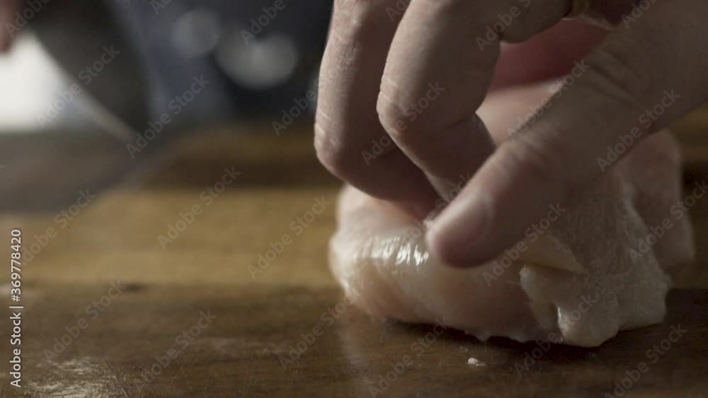 Hands cutting chicken breast with knife, close-up, slo-mo Hands cutting chicken breast with knife, close-up, slo-mo