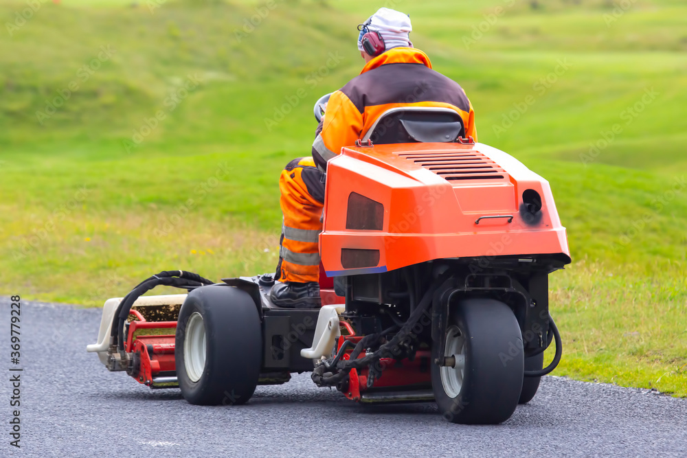 Fototapeta premium man rides on a special machine to clean the grass of the Golf course