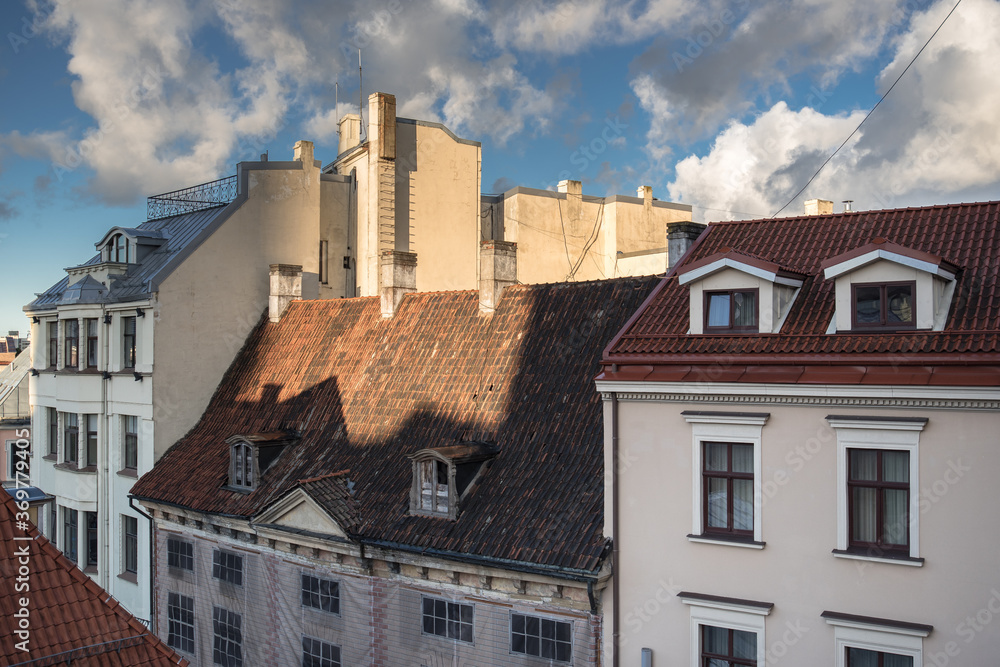 Early morning view of old houses roofs, windows, dormers, cornices, chimneys, chimney stacks chimney pots, towers, antennas in Old Town  of Riga, Latvia.