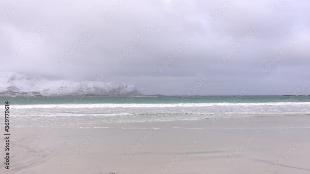 View of a snowy beach with mountains in the background in Lofoten, Norway View of a snowy beach with mountains in the background in Lofoten, Norway