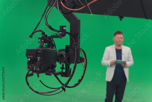 Broadcast television studio camera in greenscreen studio room with announcer on the ceiling. photo