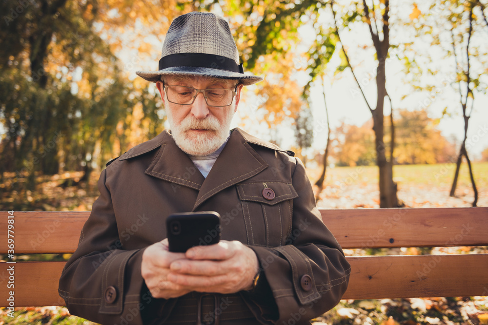 Photo of serious old man rest relax fall town center park outdoors use smartphone chatting friends send sunny weather sunshine emails wear jacket hat cap Photo of serious old man rest relax fall town center park outdoors use smartphone chatting friends send sunny weather sunshine emails wear jacket hat cap