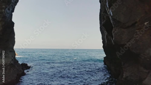 Blue Ocean Water in Gaztelugatxe, Spain with Stone Archway on a Sunny Day photo