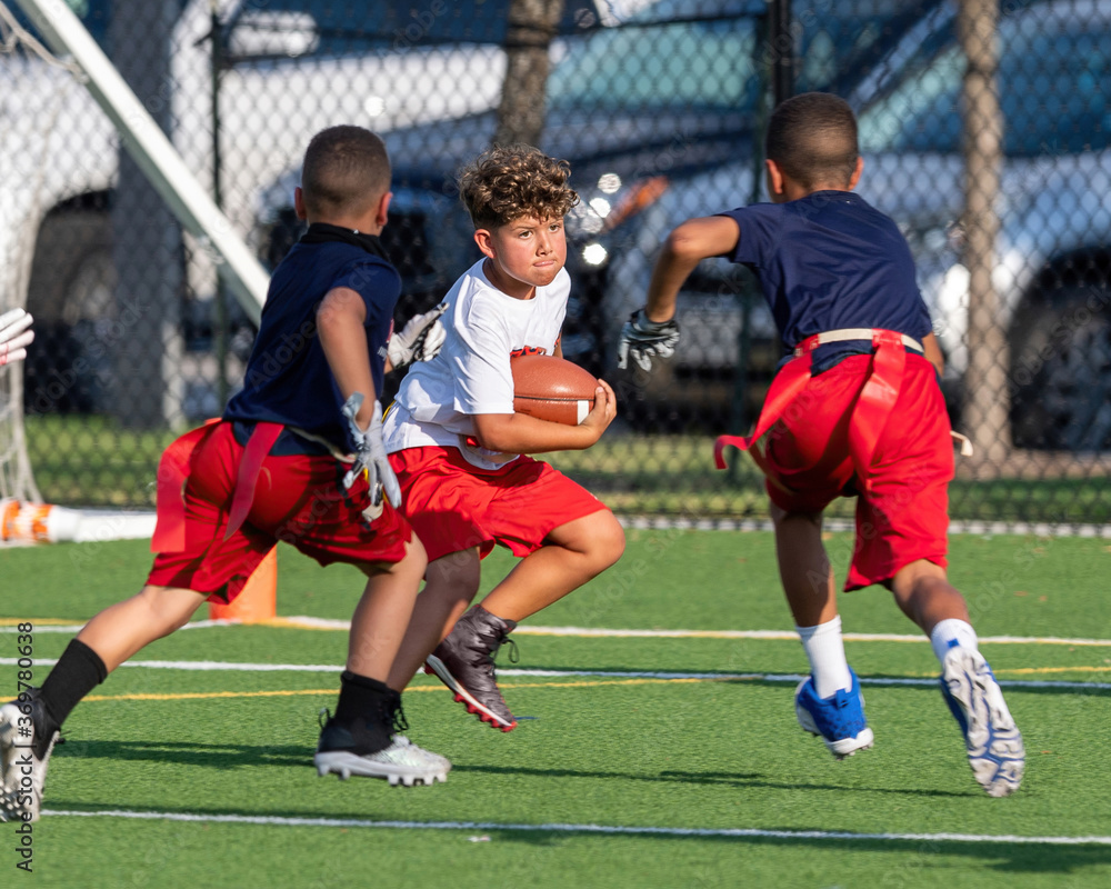 Obraz premium Cute athletic little boy playing excitedly in a flag football game