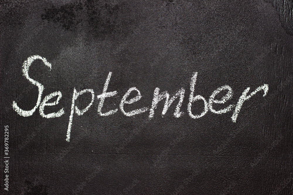 Fototapeta premium Month written in white chalk on a chalkboard. The month depicted on the chalkboard is September