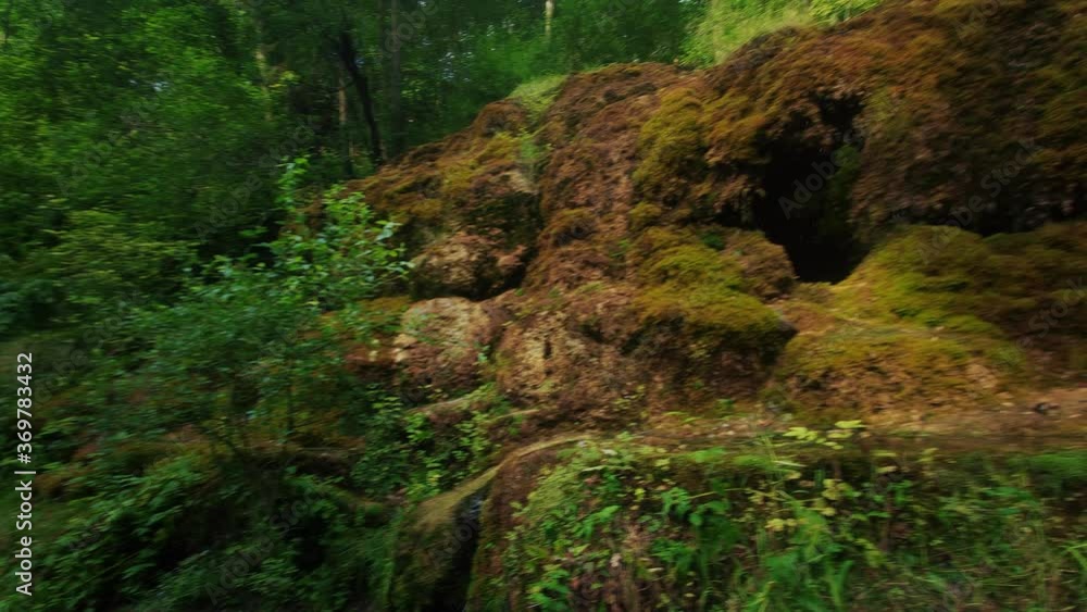 Waterfall at City Rauna, Latvia. River With a Rocky Bottom and Rauna Staburags Cliff. A Unique Rock Form of Nature Through Which the Water Flows Down the Moss and Looks Like It Cries. Waterfall at City Rauna, Latvia. River With a Rocky Bottom and Rauna Staburags Cliff. A Unique Rock Form of Nature Through Which the Water Flows Down the Moss and Looks Like It Cries.