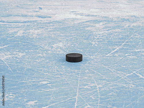 Hockey puck on blue ice hockey rink, selective focus