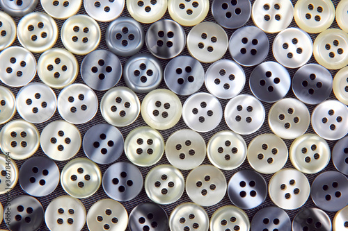 Plastic shiny buttons for clothes on a fabric background. Fashion and clothing. Factory industry.