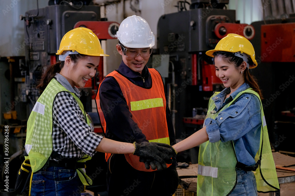 Three factory worker stand with action of hands coordination together in front of machine and they look happy. Concept of good management system of industrial business support employee for working. Three factory worker stand with action of hands coordination together in front of machine and they look happy. Concept of good management system of industrial business support employee for working.