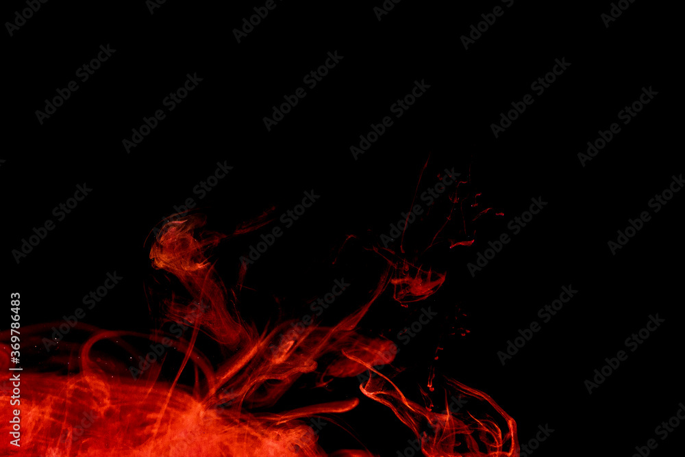 Fototapeta premium A cloud of red paint released into clear water. Isolate on a black background.