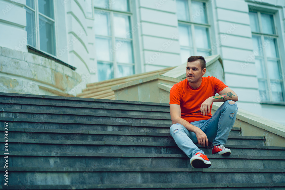 Male tourist sitting on steps of Palace. Young man poses on stairs of manor.