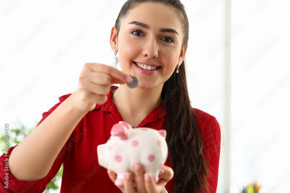 Woman putting coin in piggy bank, investments Woman putting coin in piggy bank, investments